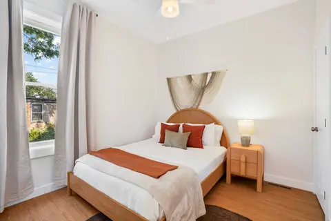 Bedroom with warm wood furniture, rust accents, and textile wall decor