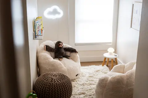 Kids’ nook with plush chairs, a knit pouf, books, and a cloud-shaped light