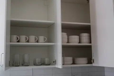 Kitchen cabinets stocked with mugs, glasses, plates, and bowls