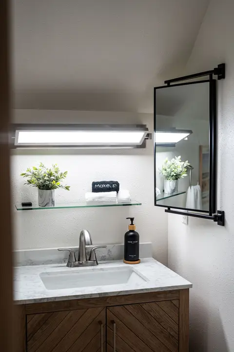 Bright bathroom vanity with an illuminated mirror and towels