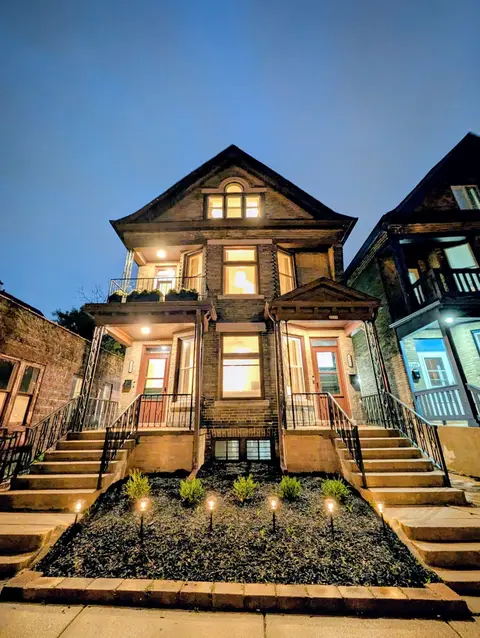 Evening view of the illuminated home with classic architectural details and front porches