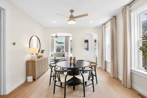 Bright dining room with seating for six, large windows, and an adjoining sitting room