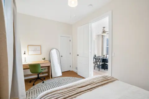 Bedroom workspace with a desk, a rolling chair, a full-length mirror, and access to the dining room
