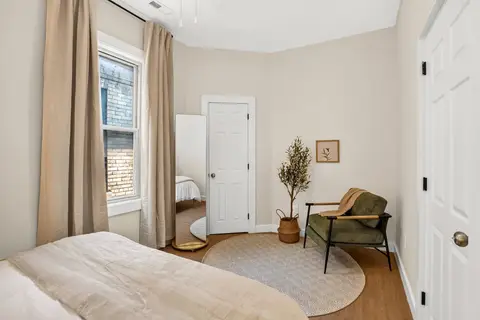 Queen bedroom with a full-length mirror and an accent chair