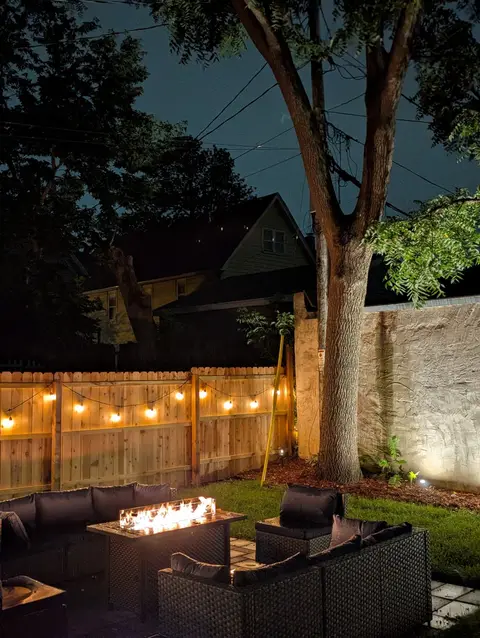 Glowing backyard fire table beneath warm string lights