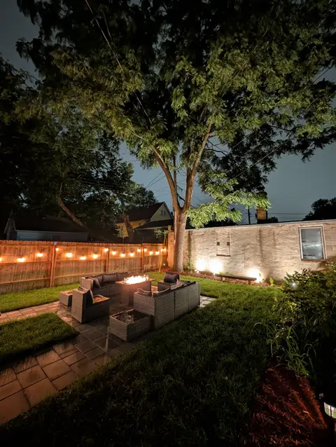 Private backyard with fire-table seating, string lights, and mature trees
