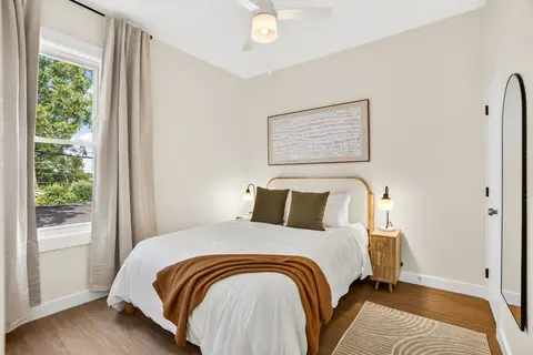 Queen bedroom with layered bedding, warm accents, and natural light
