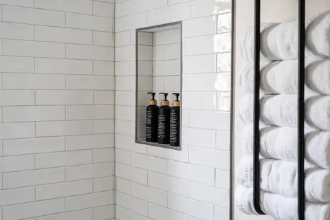 Shower stocked with body wash, shampoo, and conditioner