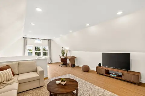 Upper lounge with a large TV, sectional seating, and a workspace