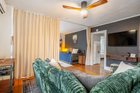 Mounted TV in the living room, with the bedroom door and the alcove behind
