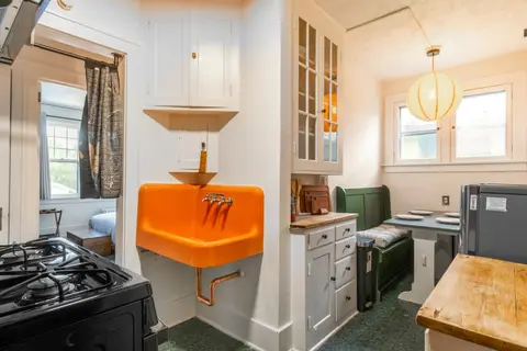 Kitchen with a gas range, the original orange farmhouse sink, and the green banquette nook