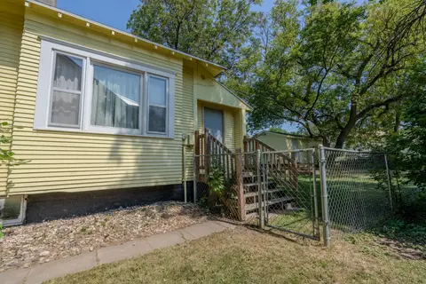 Chain-link fence and gate beside the rear entry steps of the yellow house