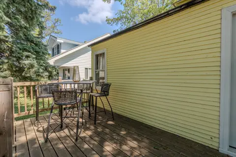 High-top table and chairs on the deck beside the yellow siding
