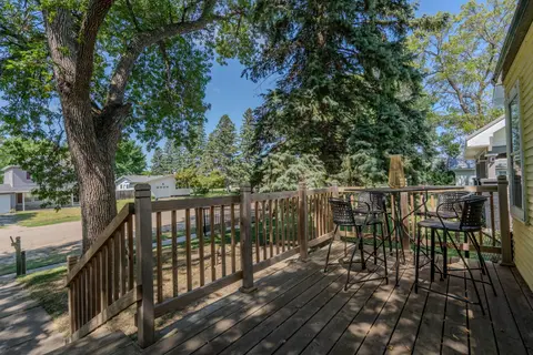 Raised deck with a high-top table and four chairs under mature trees