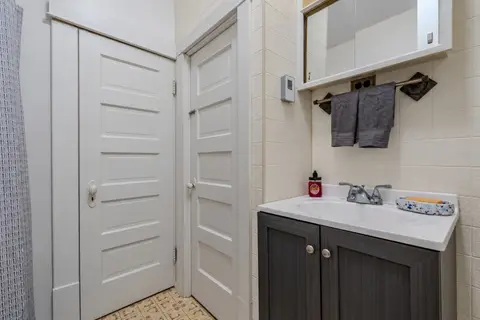 Bathroom vanity with a mirrored cabinet, a gray towel, and two white paneled doors