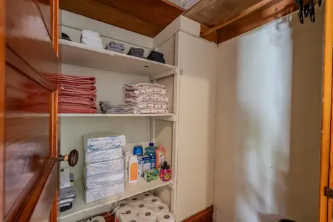 Linen closet with stacked towels, spare sheets, and cleaning supplies