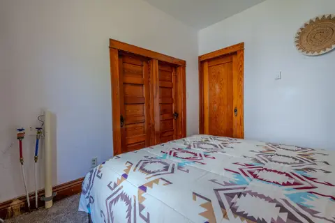 Queen bed with patterned bedding beside original wood doors