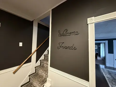 Carpeted stairs to the upstairs bedrooms, with a wood handrail
