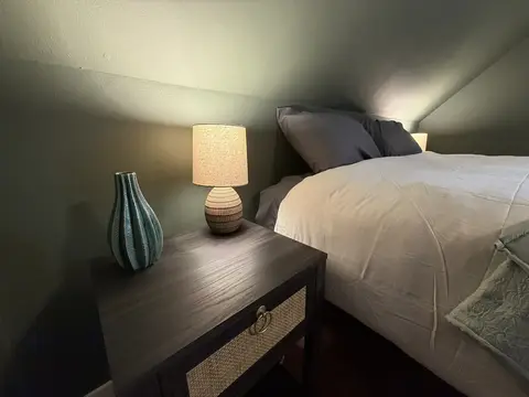 Queen bed beside a nightstand with a table lamp