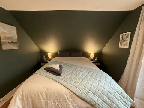 Queen bed with a pale blue quilt under a sloped ceiling