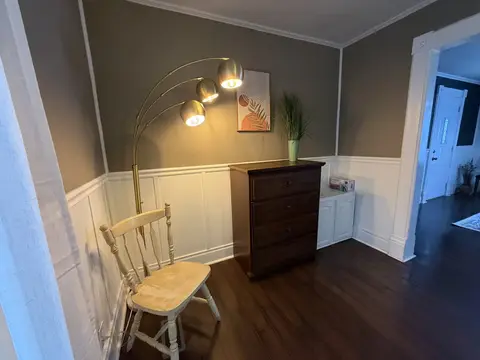 Corner nook with a wood chair, a dresser, and an arc floor lamp