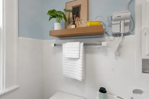 Bathroom with a floating shelf, a towel bar, and a wall-mounted hair dryer