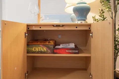 Board games in the living room cabinet, including Catan and Bezzerwizzer
