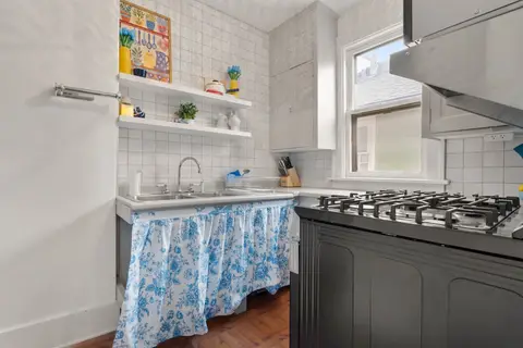 Kitchen with a double sink, open shelves, and the gas range, looking toward the window