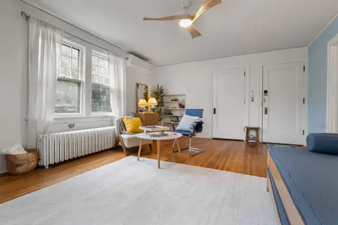 Living room with a window wall, a mini-split AC, and a reading corner, with a bench by the door