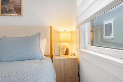 Nightstand with a lamp, carafe, and glass, plus USB-C charging by the bed