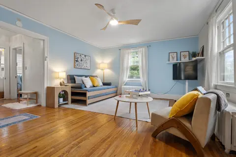 Living room with soft blue walls, original oak floors, a twin daybed with a trundle, and a reading chair