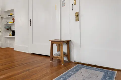 Bench, slippers, and rug by the door, where shoes come off