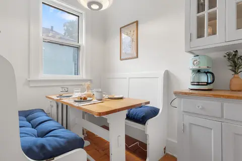 Breakfast nook with blue-cushioned bench seating and the coffee maker on the hutch
