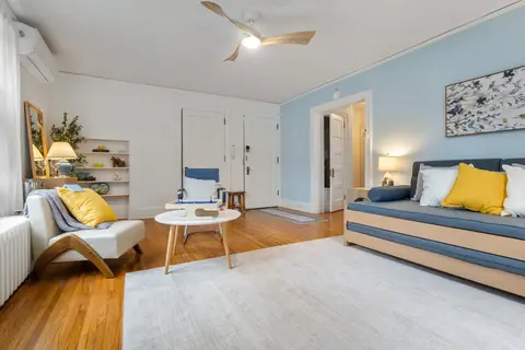 Living room with a mini-split AC, a reading corner, and built-in shelves, with the twin daybed on the right