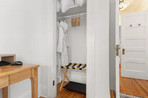 Bedroom closet with robes, hangers, and a luggage rack