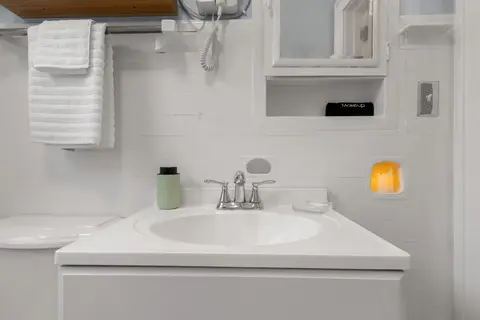 Bathroom with a vanity sink, towels, and a candle niche in the tile