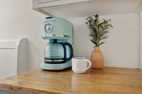 Coffee maker on the butcher-block hutch, with coffee stocked