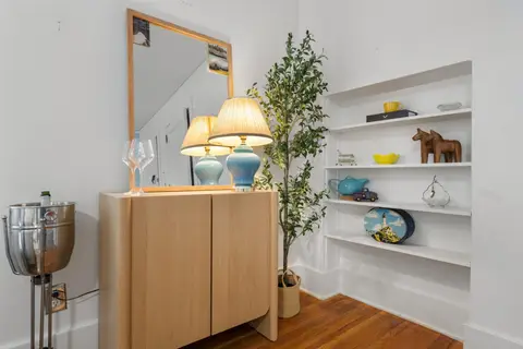 Living room cabinet with a mirror and lamps beside the built-in shelves