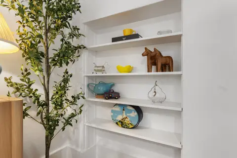 Built-in shelves with wooden Dala horses, a teapot, and a lighthouse tin