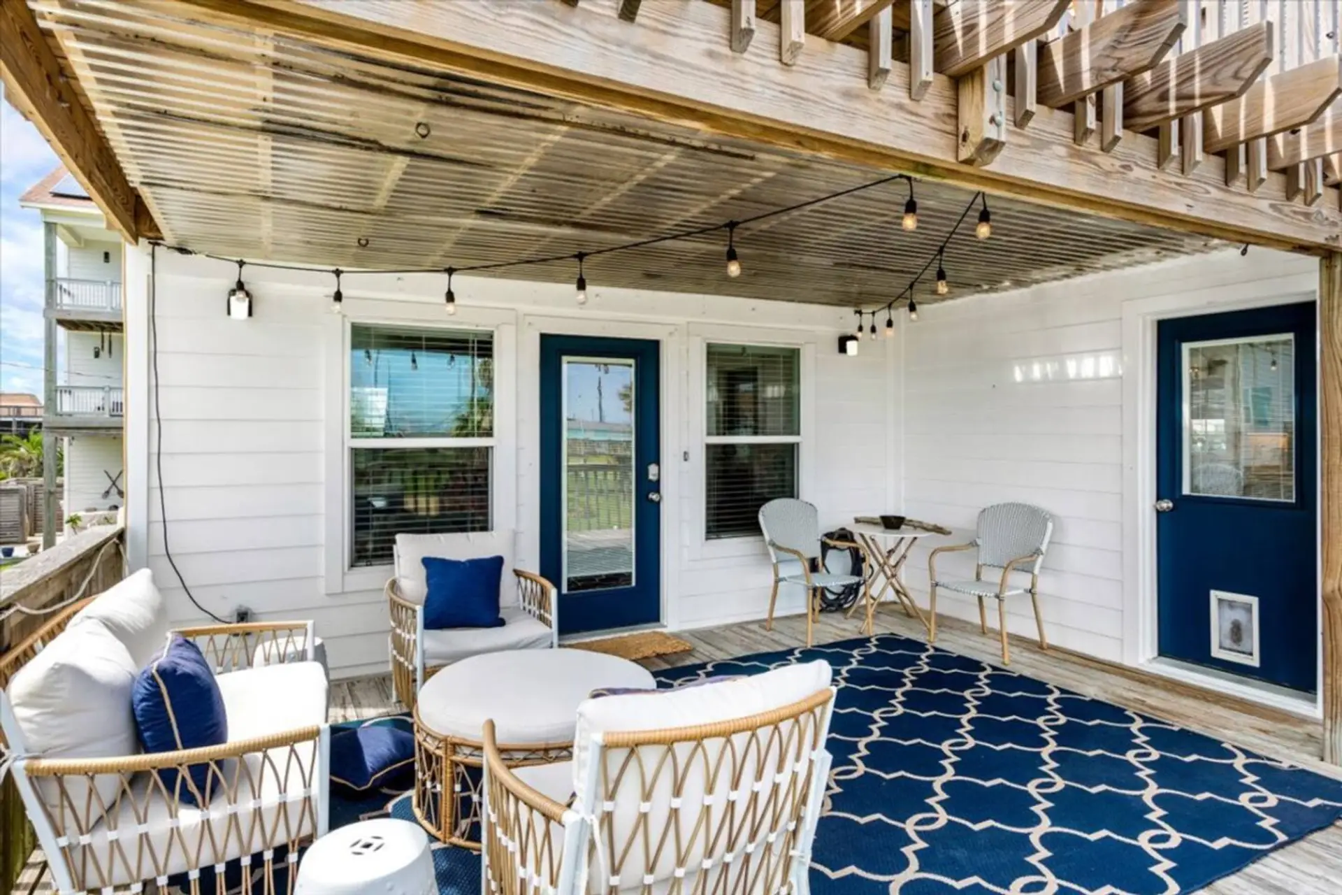 Relax beneath the string lights in this shaded patio with comfy wicker seating