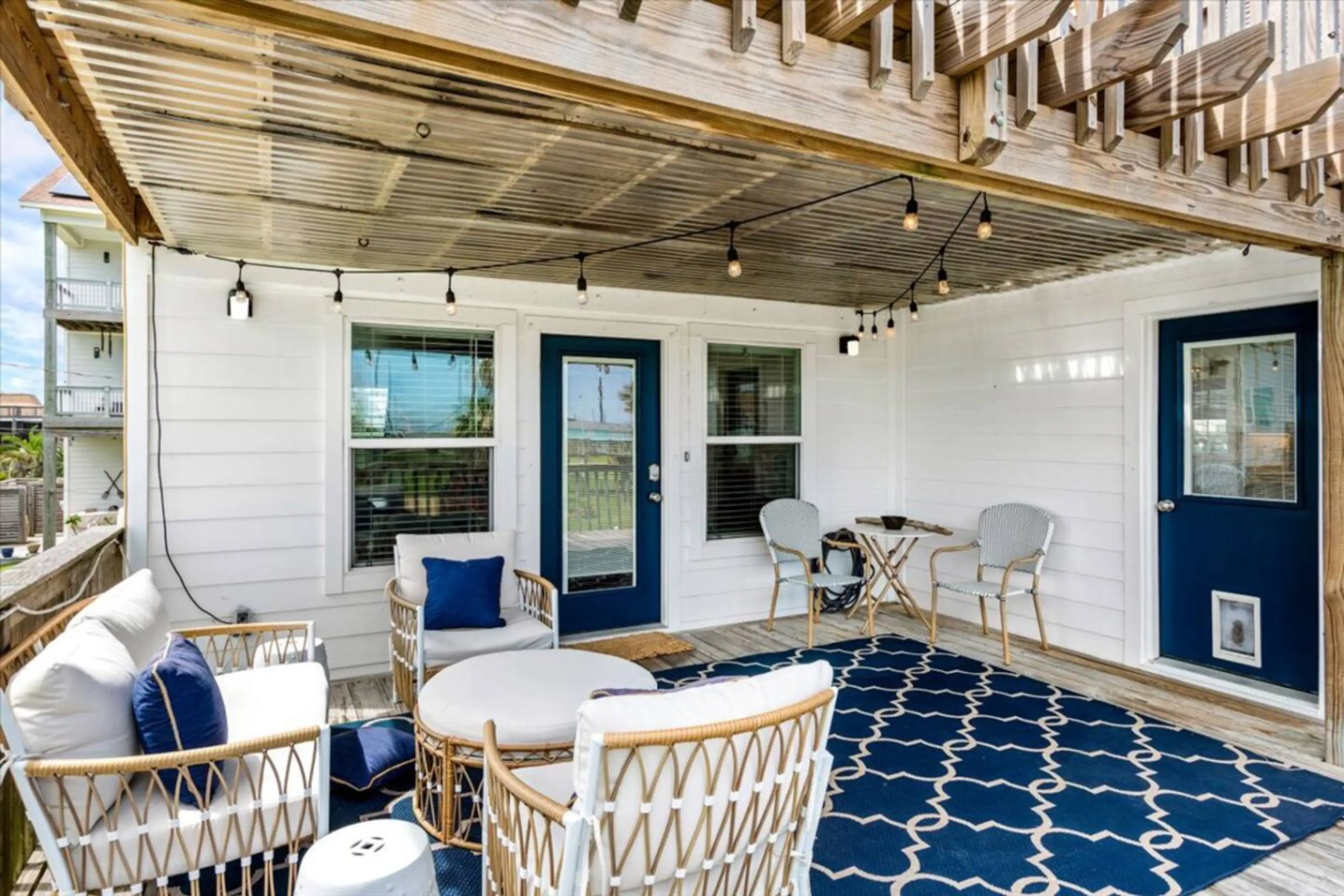 Relax beneath the string lights in this shaded patio with comfy wicker seating