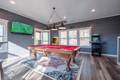 Gaming room including a pool table, two arcade games, and a large HDTV.