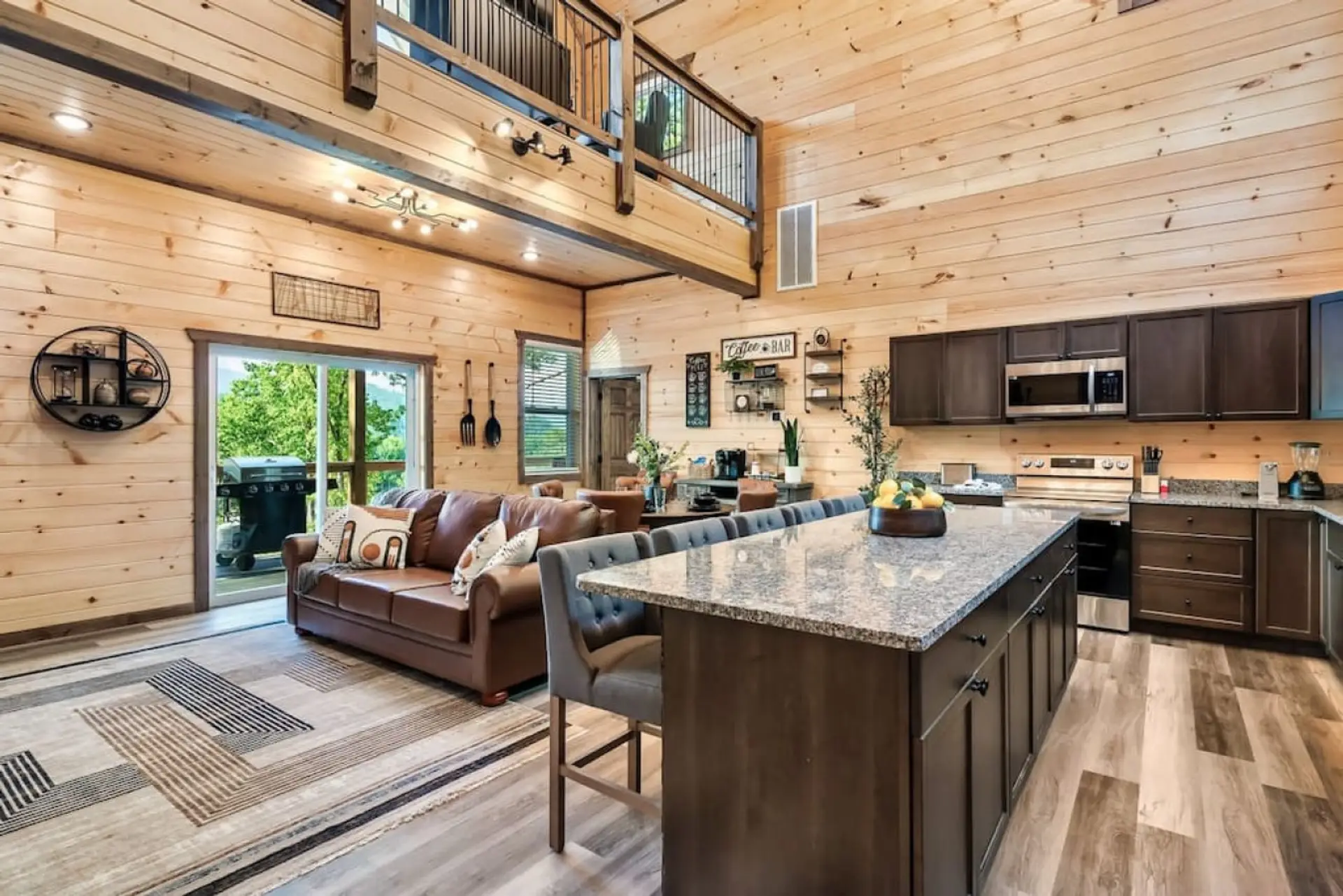 In this cabin, enjoy an open-concept living room and kitchen with direct access to the deck and breathtaking mountain views.