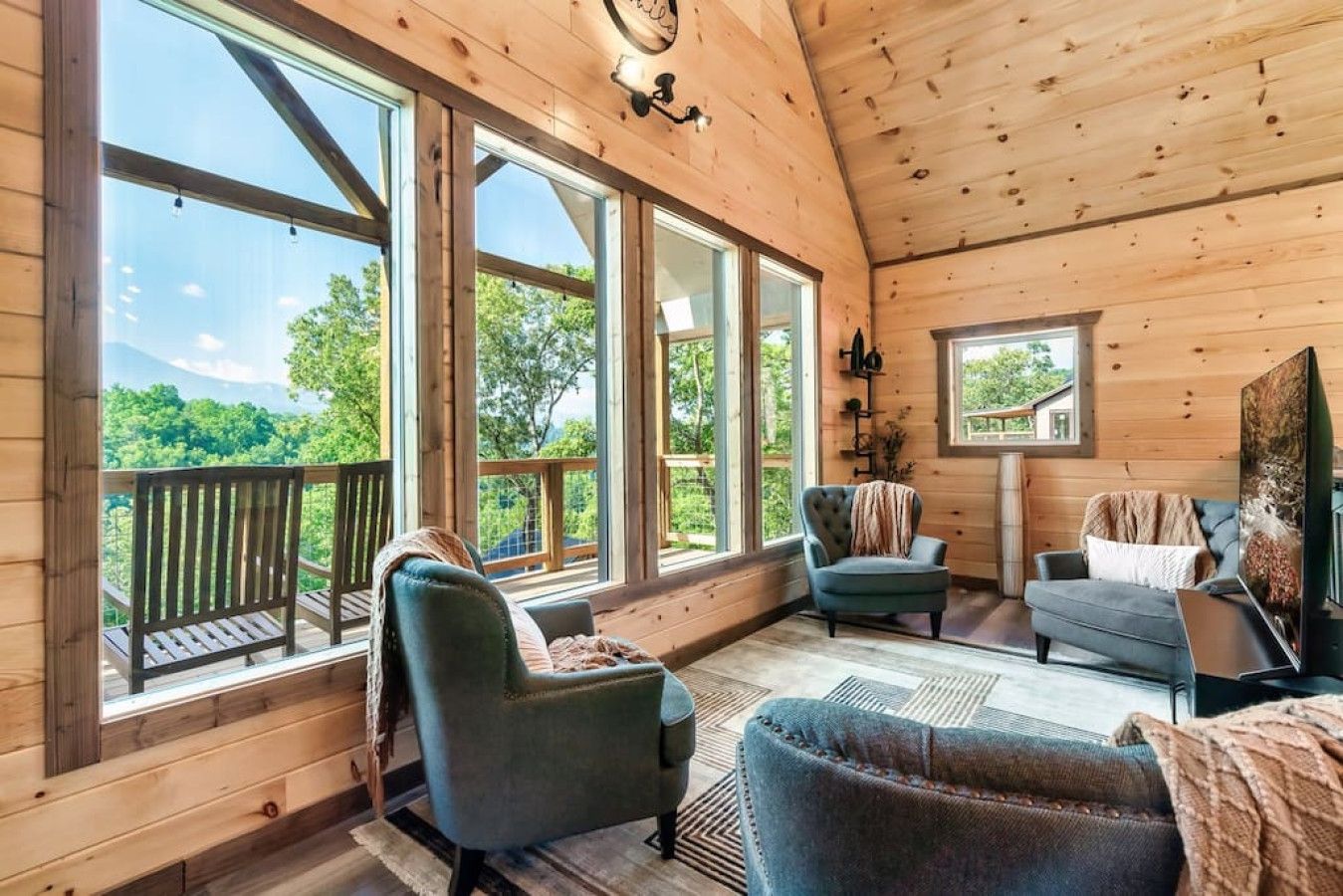 Relax in the splendor of this cabin's living room, where floor-to-ceiling windows reveal a breathtaking view of the Smoky Mountains.