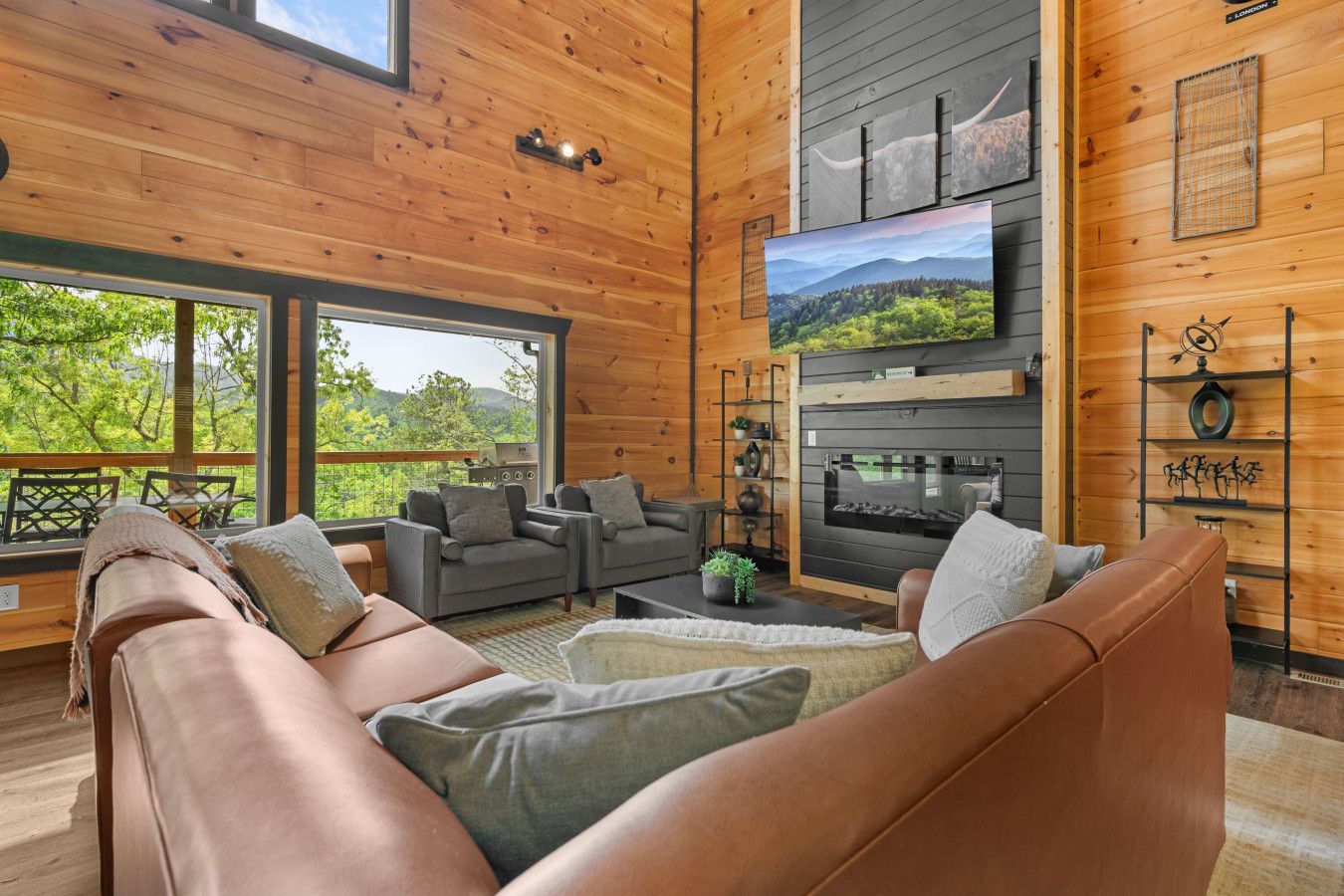 This cabin offers a spacious, cozy living room with large windows framing stunning views of the Smoky Mountains.