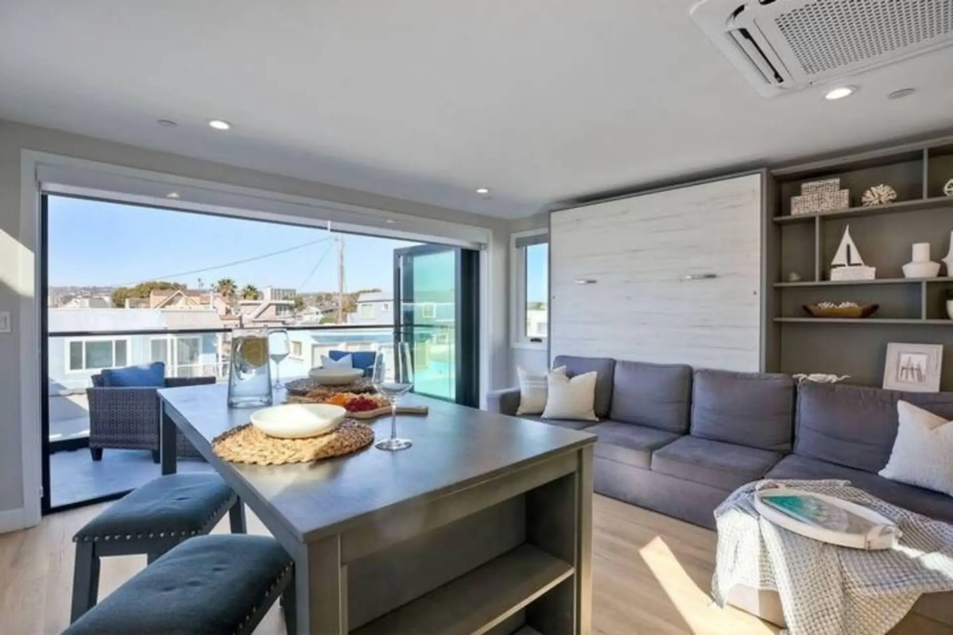 LIVING ROOM Bright open-concept living room with comfortable seating, Smart TV with streaming, and large sliding glass doors that bring in natural light and coastal breezes in this Mission Beach San Diego vacation rental.