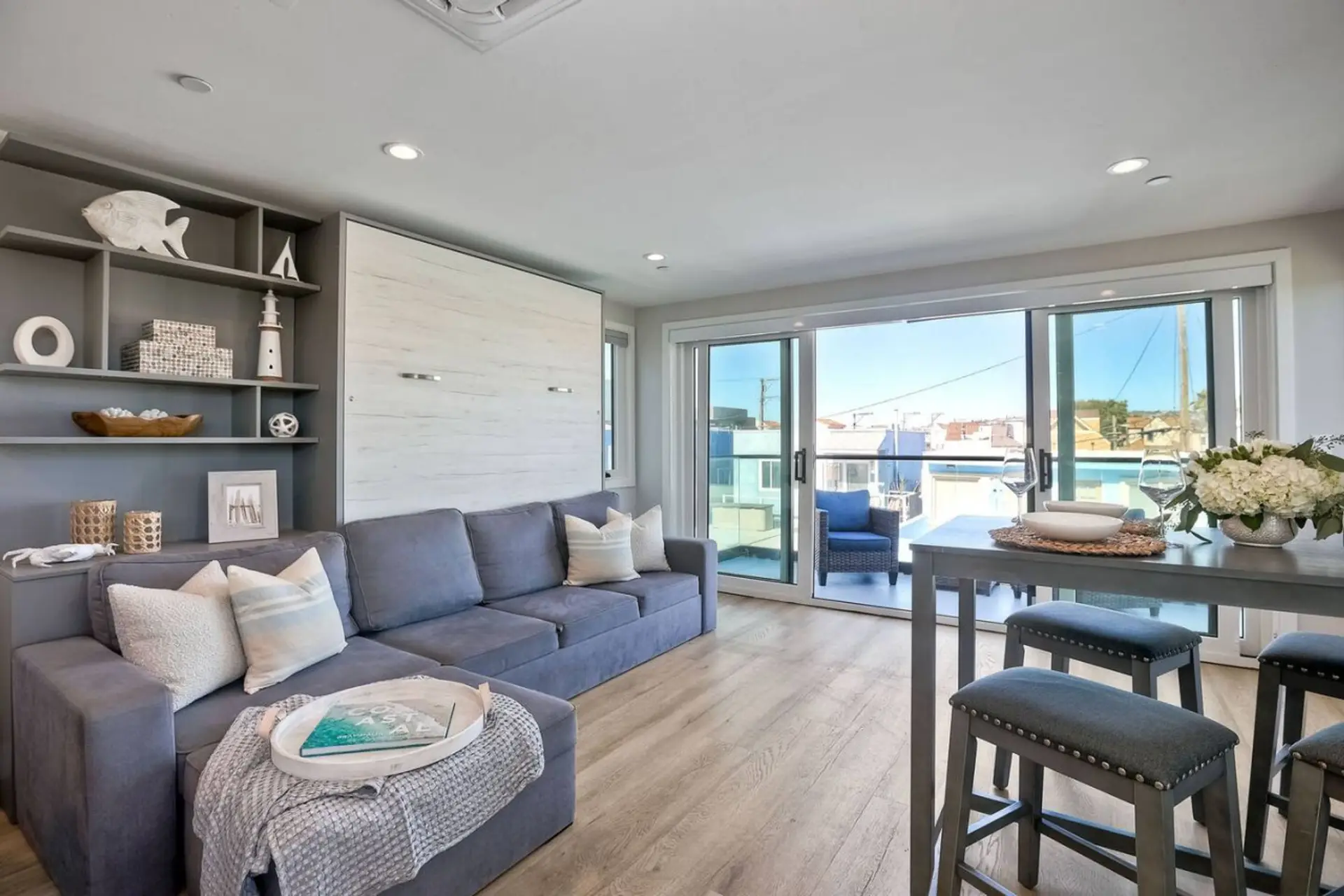 LIVING ROOM – Bright Open-Concept Living Space with Coastal Breezes - Relax in the open-concept living room featuring comfortable seating, a flat-screen smart TV with streaming access, and large sliding glass doors that bring in natural light and refreshi