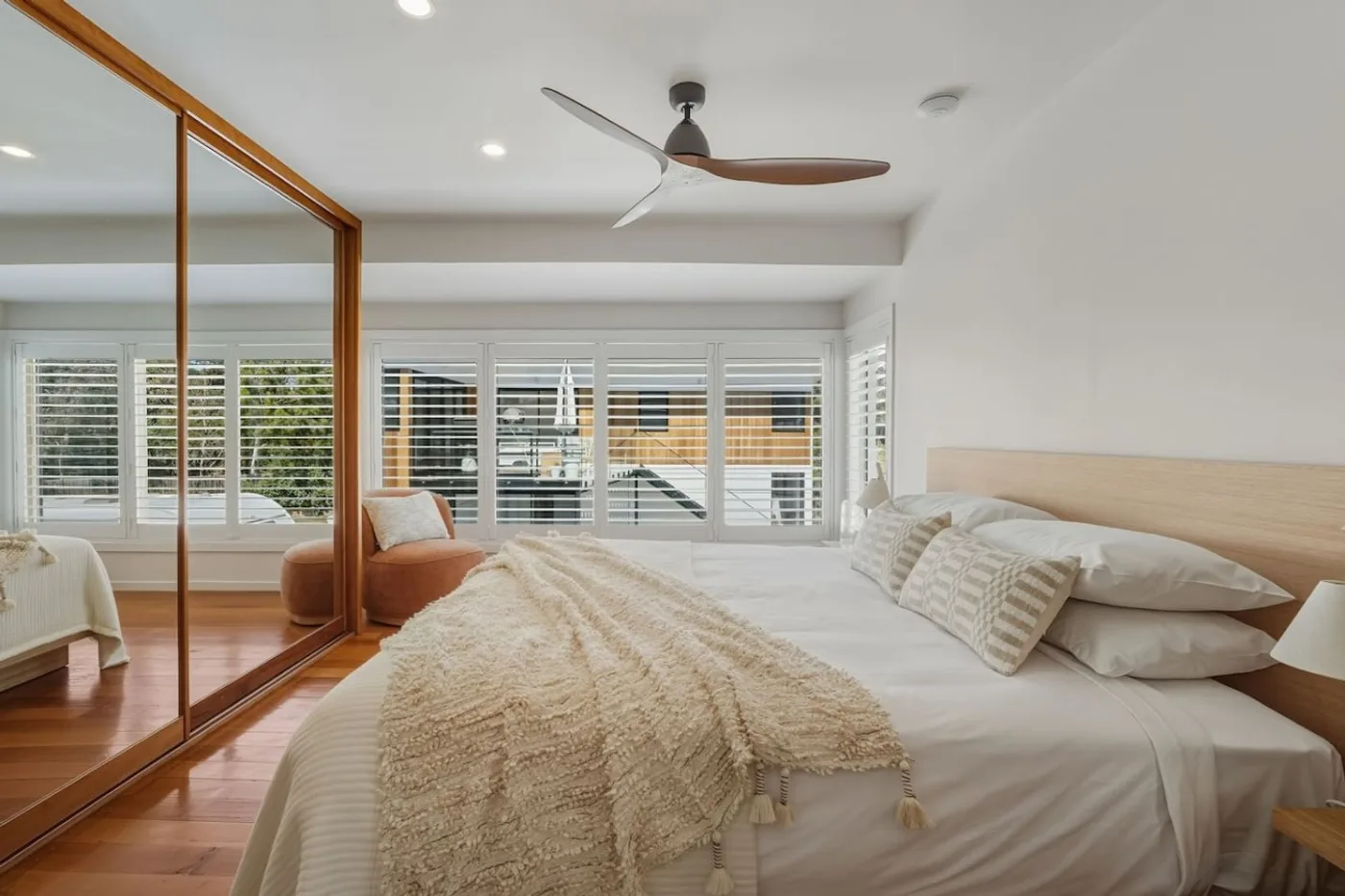 Calm king bedroom with timber floor and soft neutral bedding