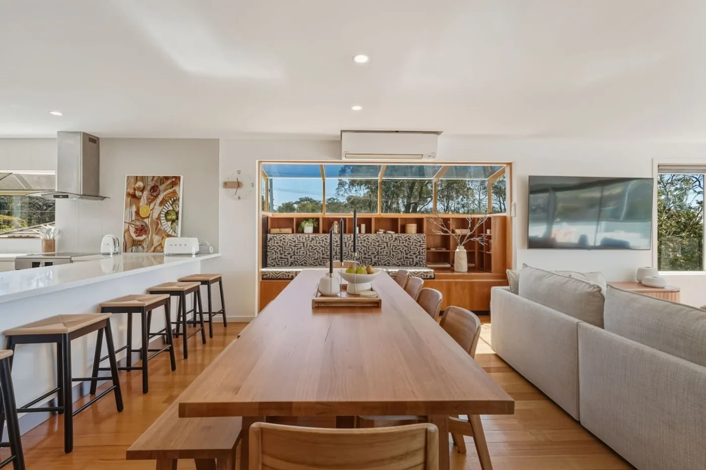 Long timber dining table beside the modern kitchen
