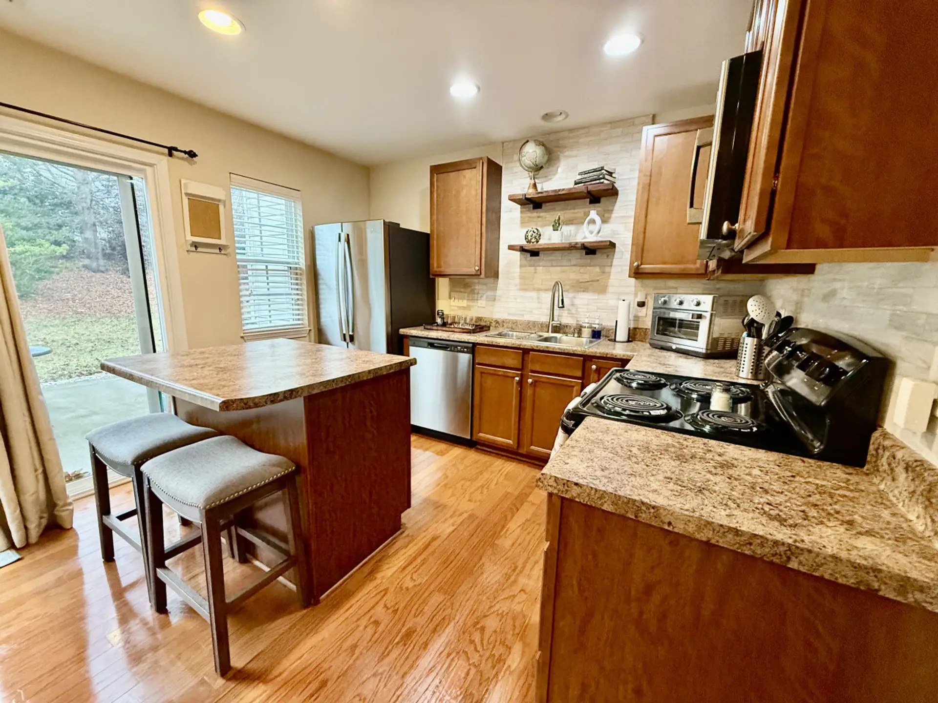 Modern and fully equipped kitchen, a cozy island with seating, and a sliding door leading to the backyard. Perfect for cooking and entertaining
